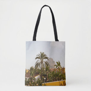 Green palm trees near brown concrete building in t tote bag