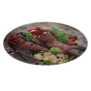 Grilled bbq steaks with fresh herbs and tomatoes cutting board