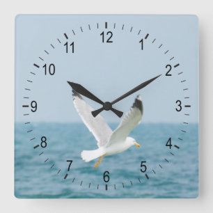 Gull flying above sea square wall clock