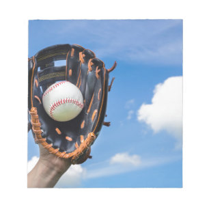 Hand holding baseball in glove with blue sky notepad