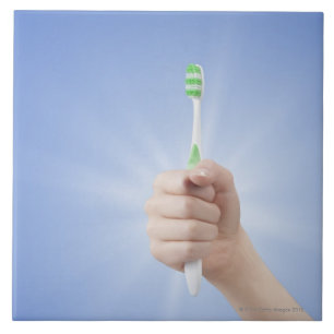 Hand holding tooth brush ceramic tile