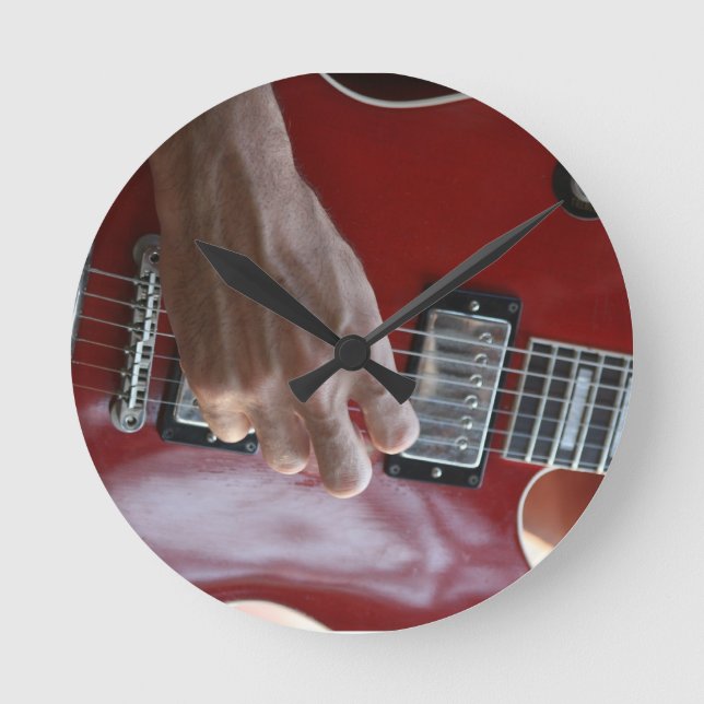 Hand playing red electric guitar near pickup round clock (Front)