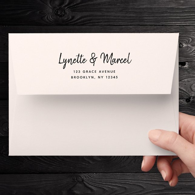 Handwritten Script 5x7 Modern Calligraphy Wedding Envelope (A hand holds a white envelope with elegant black script reading "Lynette & Marcel." )