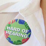 Hard of Hearing Green Pink Blue Tropical Leaves 7.5 Cm Round Badge<br><div class="desc">Another tropical hard-of-hearing badge by JessicaAmber - ask about custom orders! This button features the slogan 'Hard of Hearing' in a bold font, surrounded by a border of green, pink and blue monstera leaves. You can edit the text as needed. A great gift for your mother who wears hearing aids....</div>