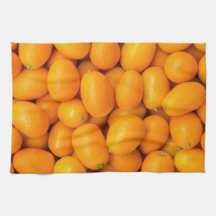 Heap of orange kumquats in cardboard box tea towel
