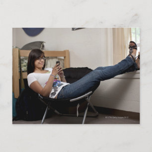 Hispanic woman hanging out in college dorm room postcard