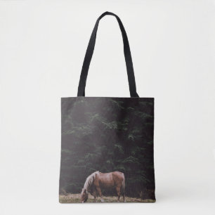 HORSE GRAZING IN THE SHADE OF CONIFERS TOTE BAG