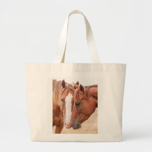 Horses nuzzling in a pasture large tote bag