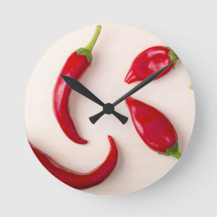 Hot red chilli peppers on a light wooden board round clock