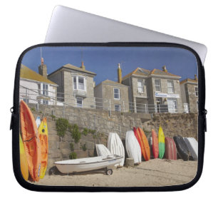 Kayaks and dinghies stacked against seawall at laptop sleeve