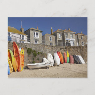 Kayaks and dinghies stacked against seawall at postcard