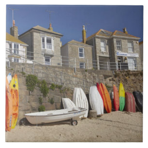 Kayaks and dinghies stacked against seawall at tile