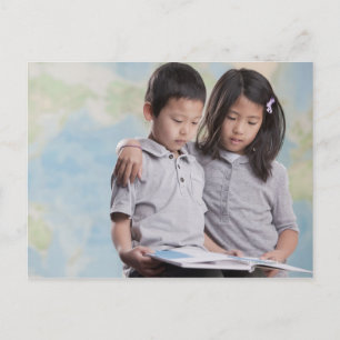 Korean children reading book near map postcard