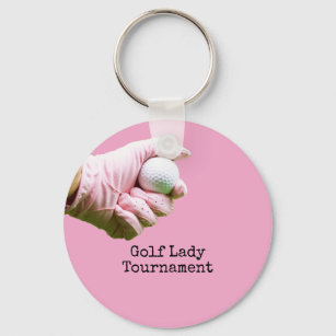 Lady golfer is holding golf ball on pinkbackground key ring