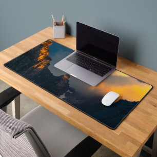 Last breath of sun shining on majestic mountains desk mat