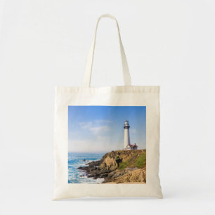 Lighthouse on hill blue sky white house ocean tote bag
