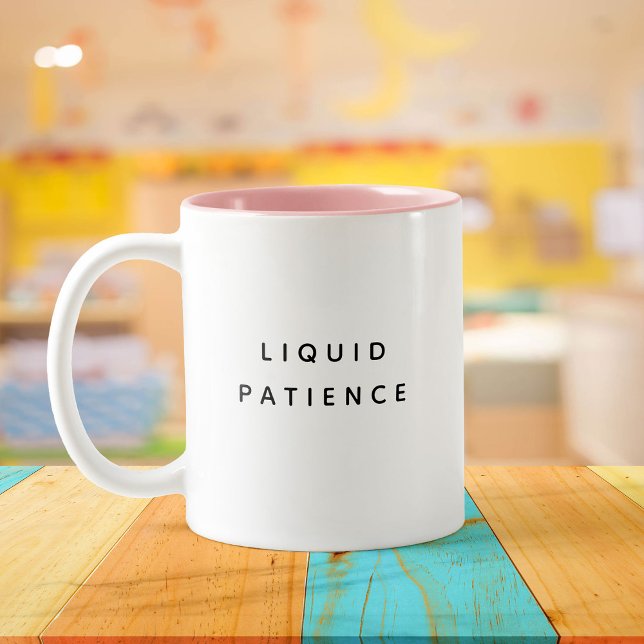 Liquid Patience Funny Cute Trendy Quote Two-Tone Coffee Mug (A white mug with "Liquid Patience" in black text sits on a colorful wooden table)