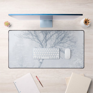 Lonely tree during snow storm in winter desk mat