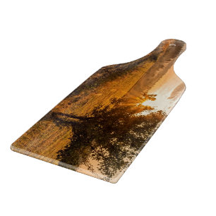 Lonely tree on the foggy field in golden sunrise cutting board