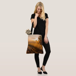 Lonely tree on the foggy field in golden sunrise tote bag