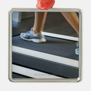 Low section of woman walking on treadmill 2 metal ornament