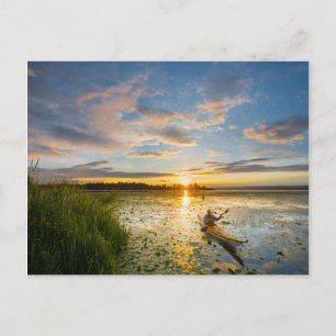 Male kayaker paddling sea kayak on still water postcard