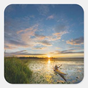 Male kayaker paddling sea kayak on still water square sticker