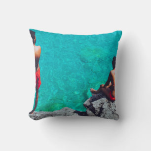 Man and woman sitting on boulder near body of wate cushion