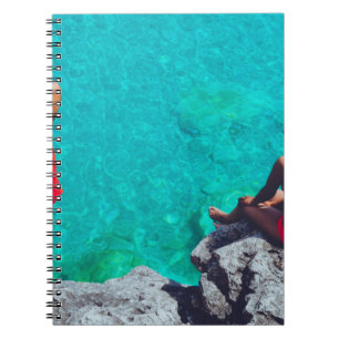 Man and woman sitting on boulder near body of wate notebook