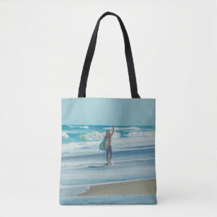 Man carrying surfboard at beach tote bag