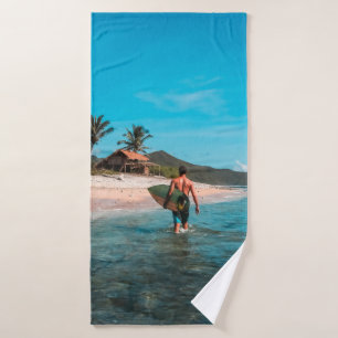 Man holding surf board in body of water bath towel