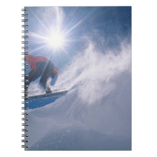 Man jumping off a large cornince on a snowboard notebook