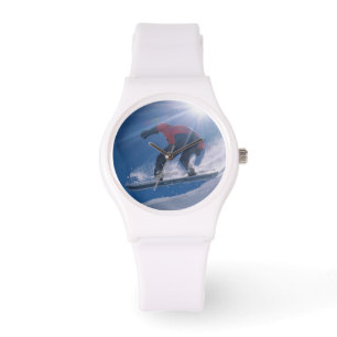 Man jumping off a large cornince on a snowboard watch