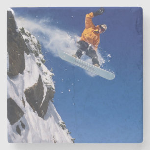Man on a snowboard jumping off a cornice at stone coaster