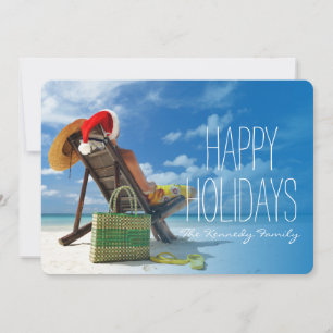 Man relaxing on the beach in santa's hat holiday card