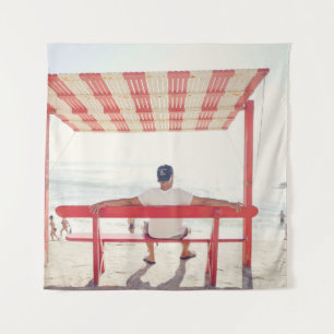 Man sitting on bench near beach tapestry