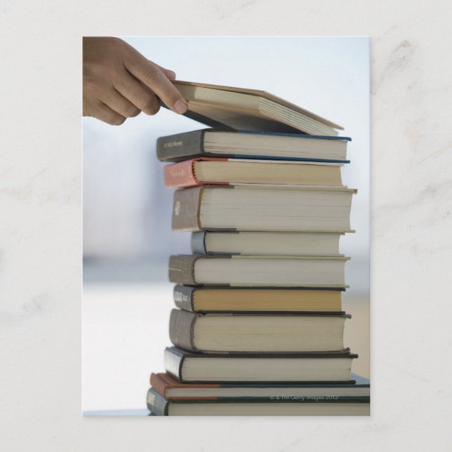 Man's hand taking a book from a stack of books postcard (Front)