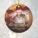 Merry Christmas Family Photo Elegant Gold Script Ceramic Ornament<br><div class="desc">Spread holiday cheer to friends and family with this modern keepsake ornament. The gold faux foil text reads "Merry Christmas" in elegant handwriting script. Replace the sample image with your favourite photo,  and add your family name and the year. A black gradient filter helps make the text pop.</div>