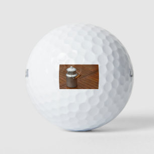 Milk can on a table golf balls