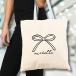 Minimalist Hand Drawn Bow Name Tote Bag<br><div class="desc">Simple Name Monogram Minimalist Canvas Tote Bag. This cute and stylish tote bag features a large hand-drawn bow at the top, paired with a name in elegant handwritten script calligraphy below. The design is showcased prominently on both sides of the bag for a bold and fashionable statement. Both the bow...</div>