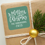 Modern Script Green Merry Christmas Custom Square Sticker<br><div class="desc">Stylish Merry Christmas holiday favour sticker features white script writing and accents of branches with holly leaves and berries. Personalise with custom name / family and year text. The green background colour can be modified.</div>