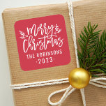 Modern Script Red Merry Christmas Custom Square Sticker<br><div class="desc">Stylish Merry Christmas holiday favour sticker features white script writing and accents of branches with holly leaves and berries. Personalise with custom name / family and year text. The crimson red background colour can be modified.</div>
