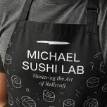 Modern Sushi Pattern with Chef Name Unique Apron<br><div class="desc">This design features a sleek black background filled with hand-drawn sushi icons in a clean line art style. Bold white typography highlights a culinary studio theme, paired with a minimalist knife graphic and an elegant subtitle for a polished, professional look. The monochrome palette gives it a modern, upscale feel that...</div>