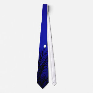 Moon in trees against deep blue sky tie