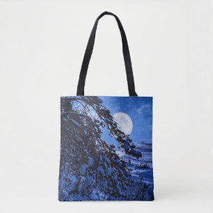Moon over snowy fir tree and sea coast at night tote bag