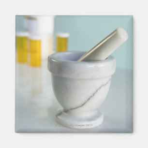 Mortar and pestle, pill bottles in background magnet