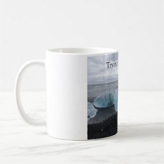 Mug with ice on black beach