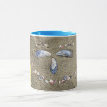 Mug yellow face made in the sand with sea shells