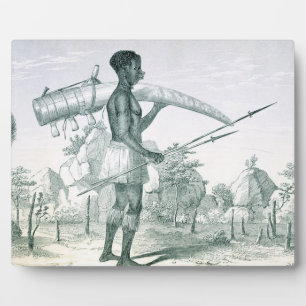 Native carrying a decorated ivory elephant tusk, f plaque