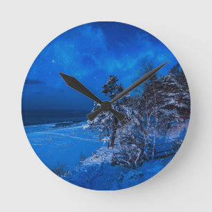 Nighttime winter scene with snow covered pines round clock
